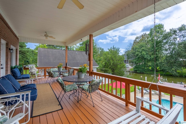 wooden terrace featuring ceiling fan, outdoor dining space, and a water view