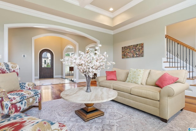 living area with baseboards, stairs, ornamental molding, wood finished floors, and arched walkways