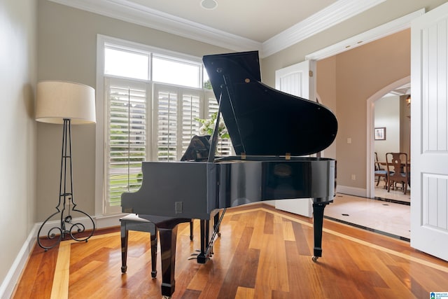 sitting room with arched walkways, plenty of natural light, wood finished floors, and crown molding