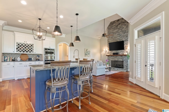 kitchen featuring decorative backsplash, dark stone countertops, double oven, and white cabinets