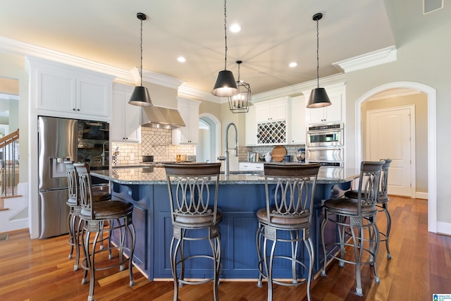 kitchen with arched walkways, white cabinets, stainless steel appliances, and ornamental molding