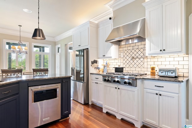 kitchen featuring stainless steel appliances, wall chimney exhaust hood, crown molding, and white cabinets