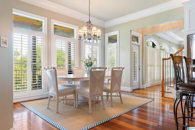 dining room with an inviting chandelier, crown molding, wood finished floors, and baseboards