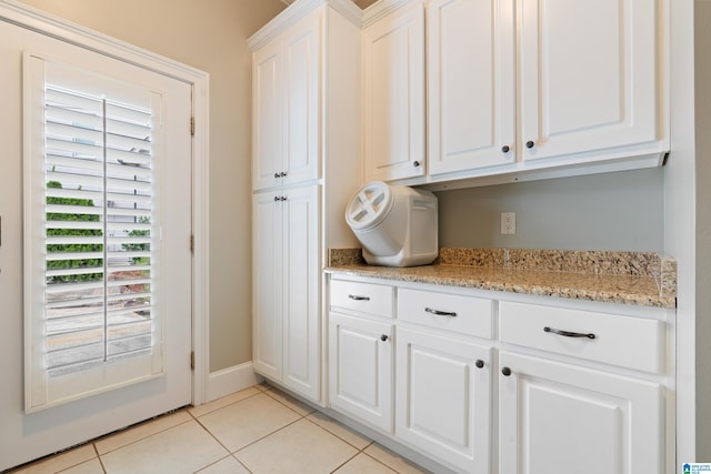 kitchen featuring light stone counters, baseboards, white cabinets, and light tile patterned flooring