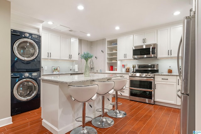 kitchen featuring open shelves, white cabinetry, stainless steel appliances, stacked washer / dryer, and wood tiled floor