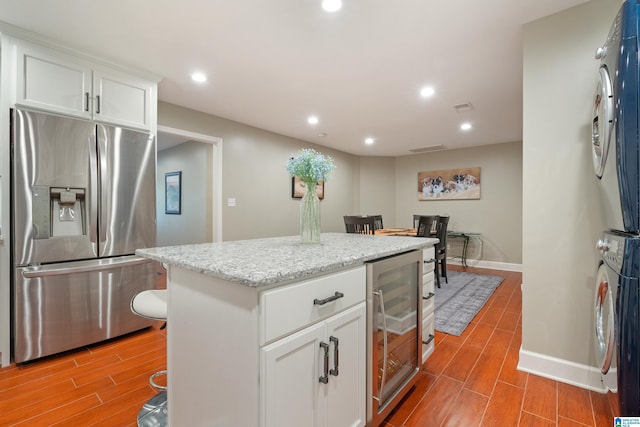 kitchen featuring wood tiled floor, recessed lighting, wine cooler, stacked washer / drying machine, and stainless steel fridge