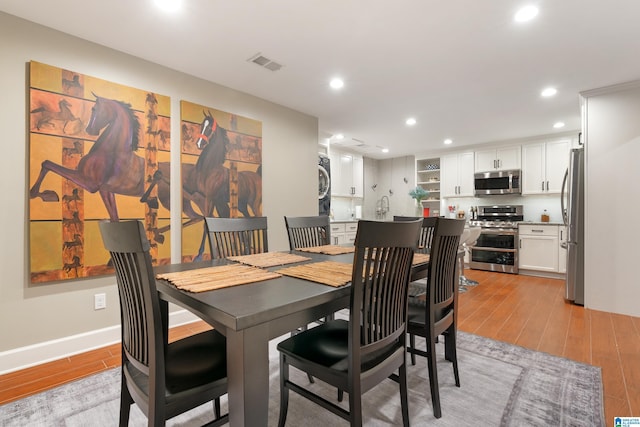 dining room featuring visible vents, recessed lighting, stacked washing maching and dryer, and light wood-type flooring