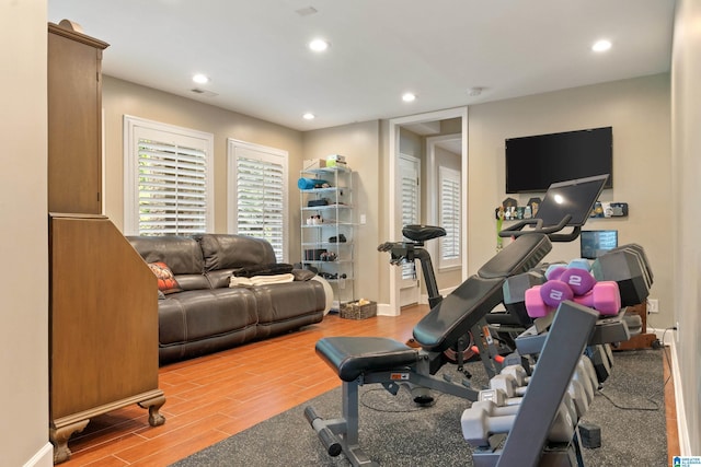 workout room featuring recessed lighting, baseboards, and wood finished floors