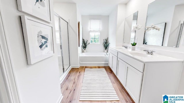 bathroom with wood finished floors, a sink, a bath, and a shower stall