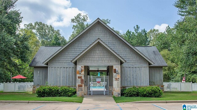 view of front of property with board and batten siding, a front yard, and fence