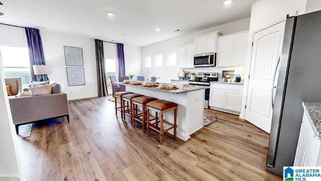 kitchen featuring appliances with stainless steel finishes, a healthy amount of sunlight, white cabinetry, and a center island