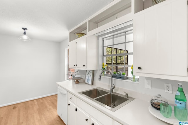 kitchen with light wood-type flooring, white dishwasher, sink, hanging light fixtures, and white cabinets