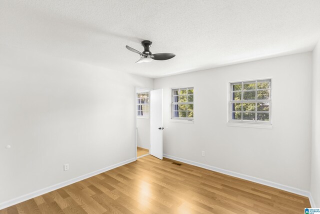 empty room with a textured ceiling, ceiling fan, and light hardwood / wood-style floors