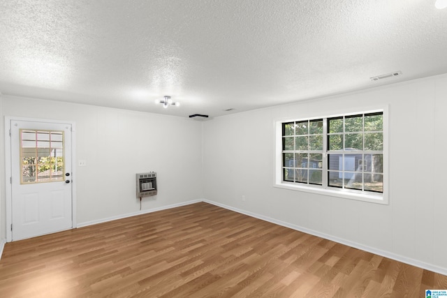 spare room with wood-type flooring, heating unit, and a textured ceiling