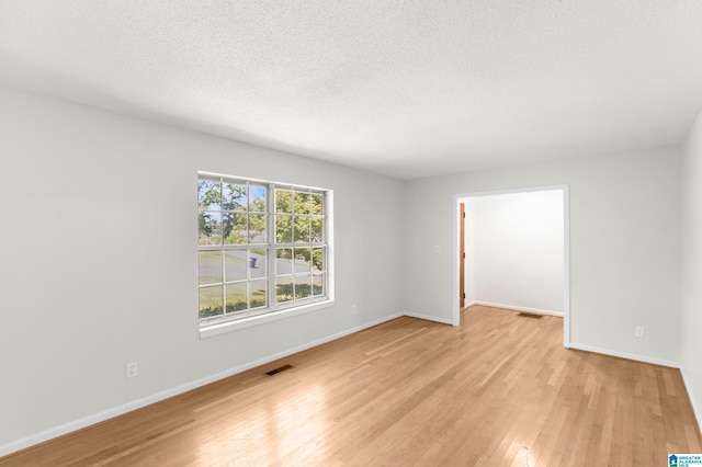 unfurnished room featuring light wood-type flooring and a textured ceiling