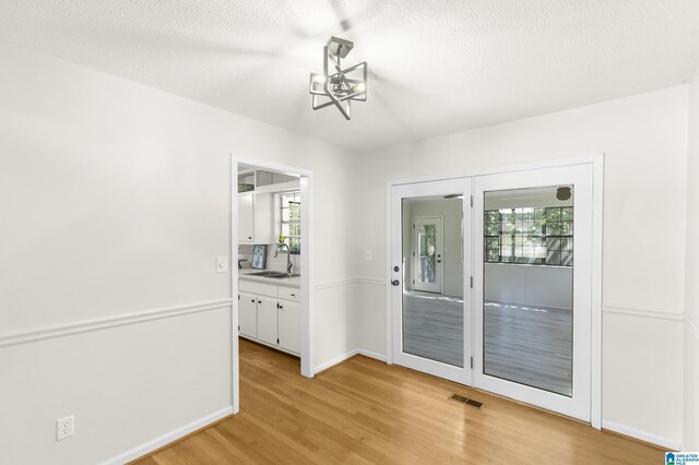 interior space featuring light wood-type flooring, a textured ceiling, a wealth of natural light, and sink