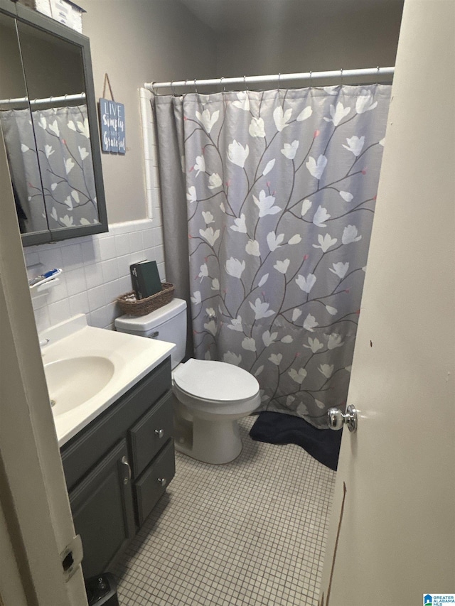 bathroom with tile patterned floors, vanity, toilet, and tile walls