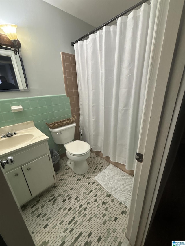 bathroom with a shower with shower curtain, tile patterned floors, vanity, tile walls, and toilet