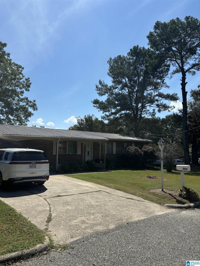 ranch-style home with metal roof, concrete driveway, and a front yard