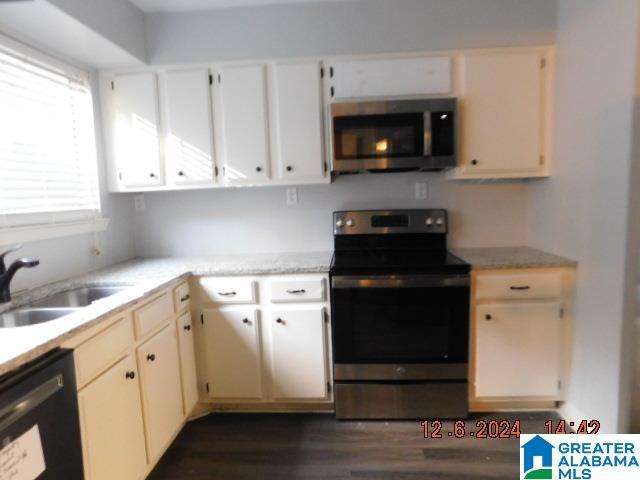 kitchen with dark wood finished floors, appliances with stainless steel finishes, cream cabinets, light countertops, and a sink