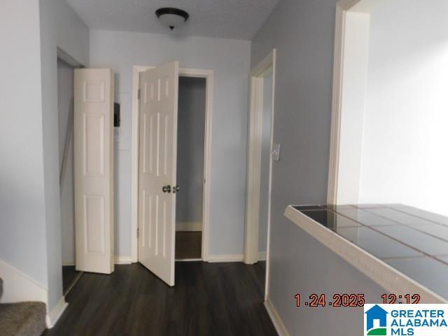 hall featuring dark wood-style floors, baseboards, and stairway