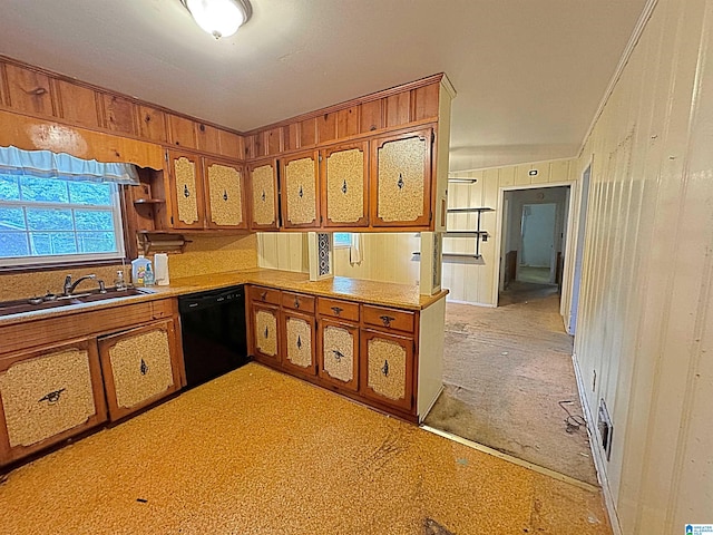 kitchen featuring black dishwasher, wood walls, and sink