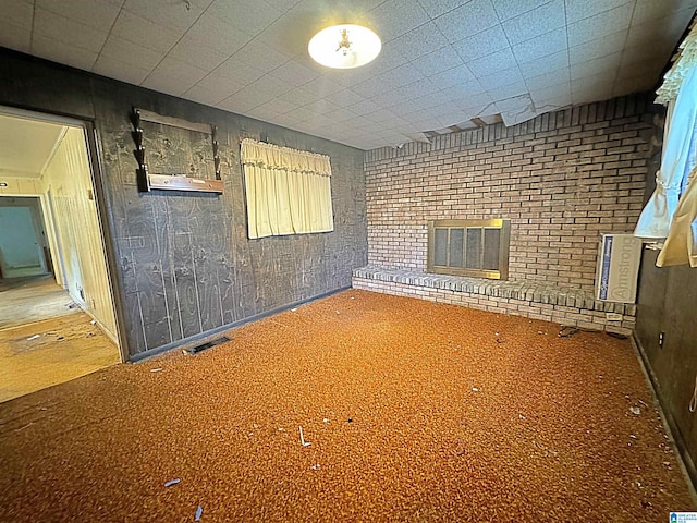 carpeted empty room featuring wood walls and a fireplace