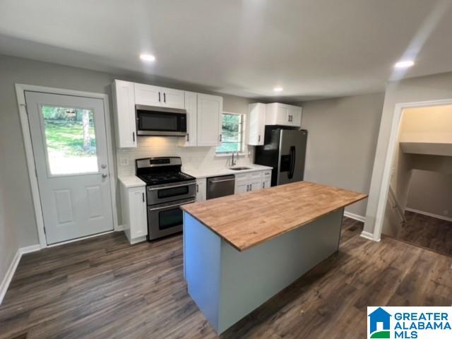 kitchen featuring backsplash, butcher block counters, appliances with stainless steel finishes, and dark hardwood / wood-style flooring