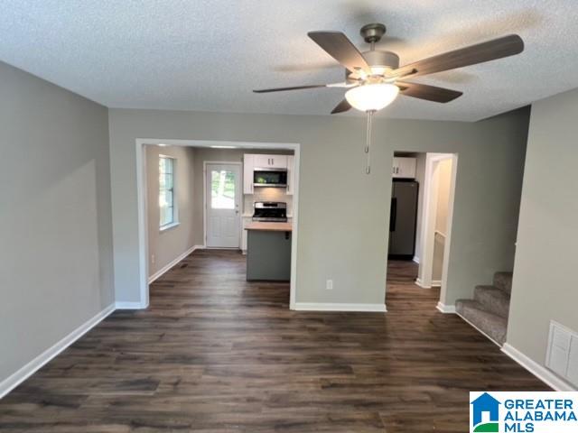 interior space featuring dark wood-type flooring, ceiling fan, and a textured ceiling