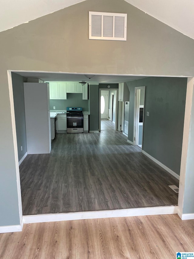 unfurnished living room with wood-type flooring and vaulted ceiling