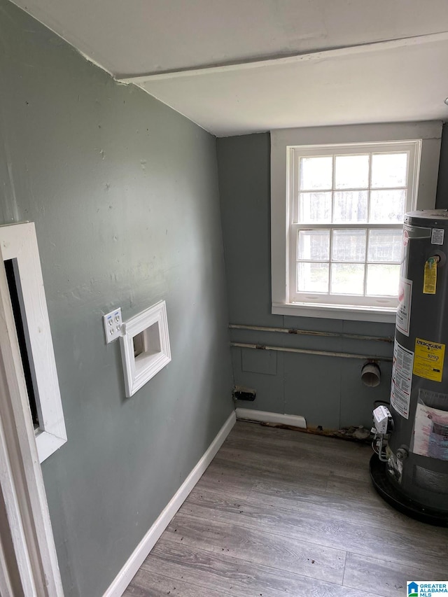 clothes washing area with wood-type flooring and water heater