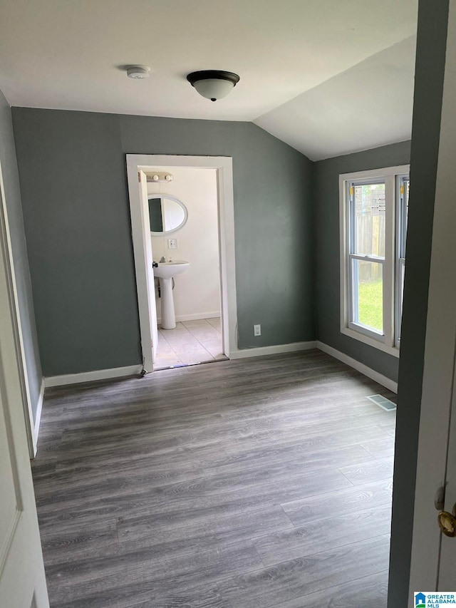 unfurnished room featuring lofted ceiling, light hardwood / wood-style floors, and sink