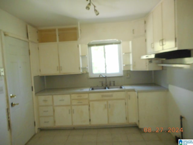 kitchen with cream cabinetry, light tile patterned floors, and sink