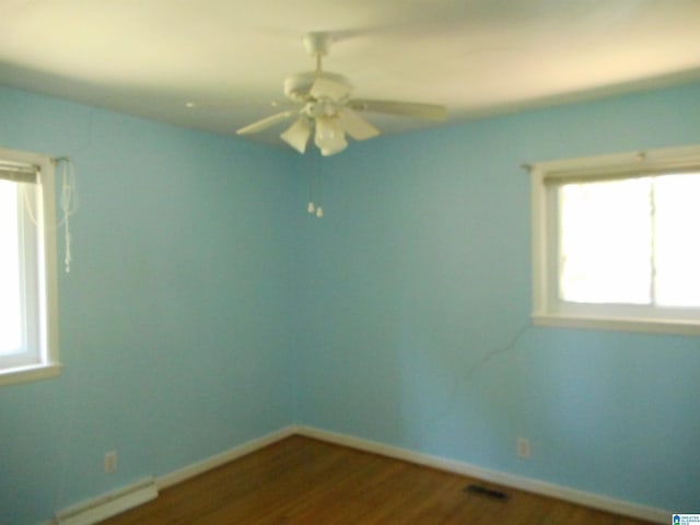 unfurnished room with dark wood-style floors, a baseboard radiator, visible vents, ceiling fan, and baseboards