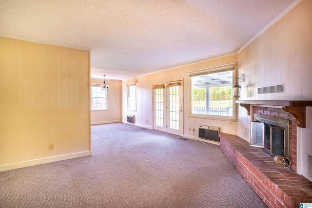 unfurnished living room with a textured ceiling, heating unit, carpet, and a fireplace