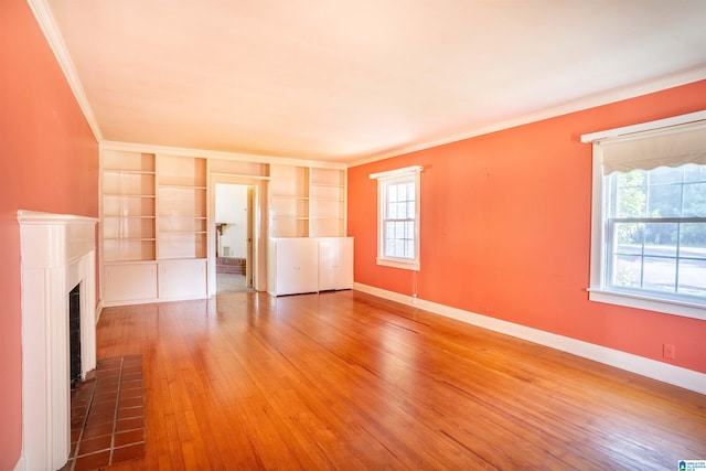 unfurnished living room with a fireplace, crown molding, hardwood / wood-style floors, and built in shelves