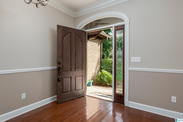 foyer entrance with ornamental molding, baseboards, and wood finished floors