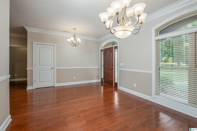 empty room with a chandelier, ornamental molding, and wood finished floors