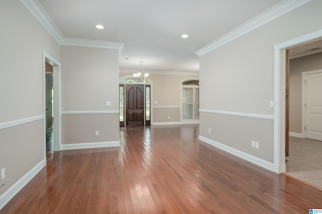 spare room with a notable chandelier, recessed lighting, ornamental molding, wood finished floors, and baseboards