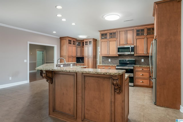 kitchen featuring visible vents, appliances with stainless steel finishes, tasteful backsplash, brown cabinetry, and a center island with sink