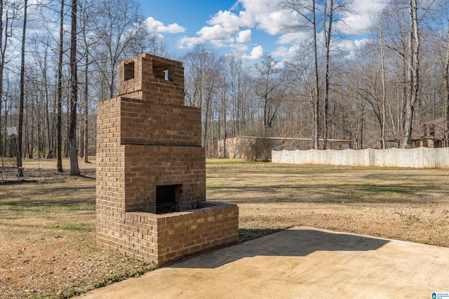 view of yard with a patio area, an outdoor brick fireplace, and fence