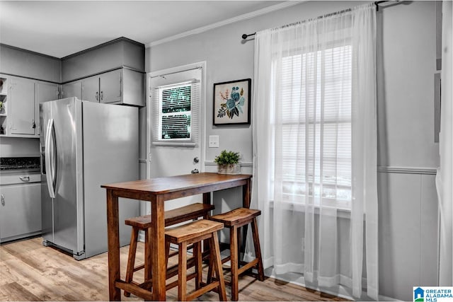 kitchen with light wood-type flooring, stainless steel fridge with ice dispenser, and ornamental molding