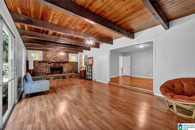 living room with wooden ceiling, beamed ceiling, hardwood / wood-style floors, and a stone fireplace