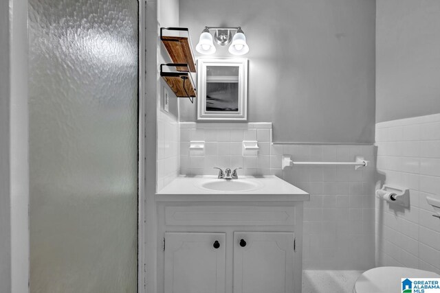 bathroom with tile walls, toilet, and vanity