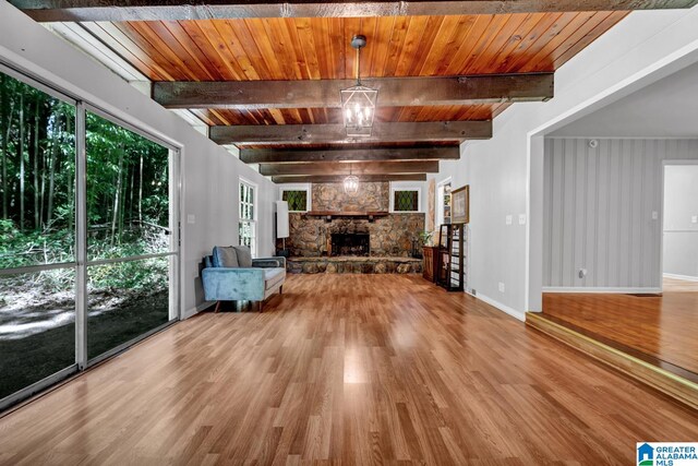 unfurnished living room featuring hardwood / wood-style floors, wood ceiling, beam ceiling, and a stone fireplace