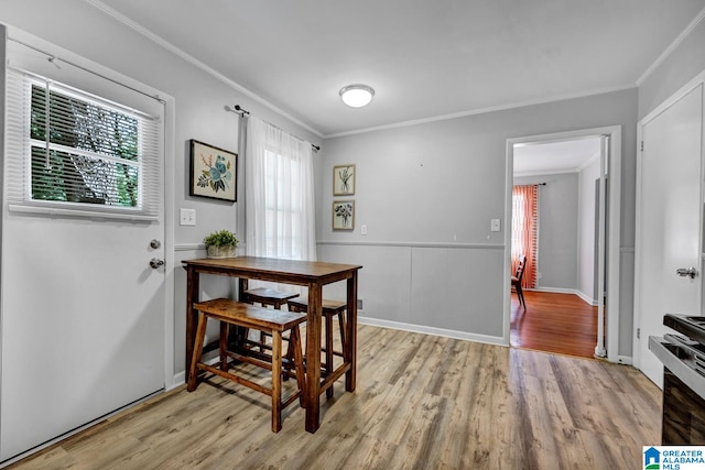 dining room featuring light wood-type flooring and crown molding