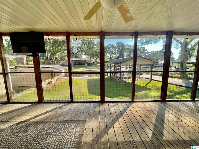 unfurnished sunroom with a healthy amount of sunlight, ceiling fan, and wooden ceiling