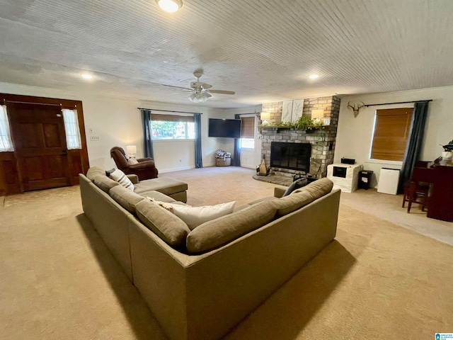 carpeted living room featuring a large fireplace and ceiling fan