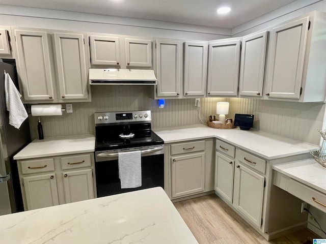 kitchen with refrigerator, ventilation hood, light stone counters, electric stove, and light wood-type flooring