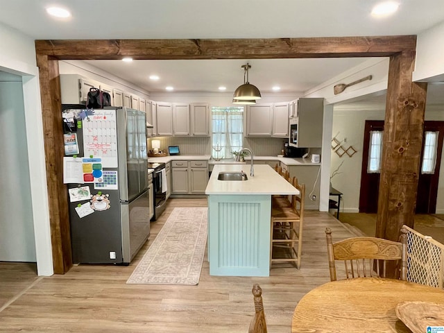 kitchen featuring decorative light fixtures, a center island with sink, electric range oven, stainless steel refrigerator, and sink